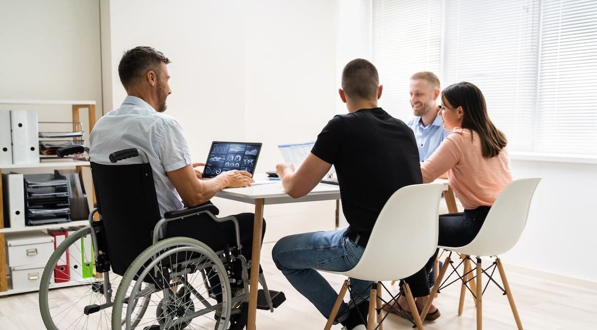 Eine diverse Gruppe von Kolleginnen und Kollegen unterschiedlicher Ethnien, die lächelnd zusammenarbeiten.